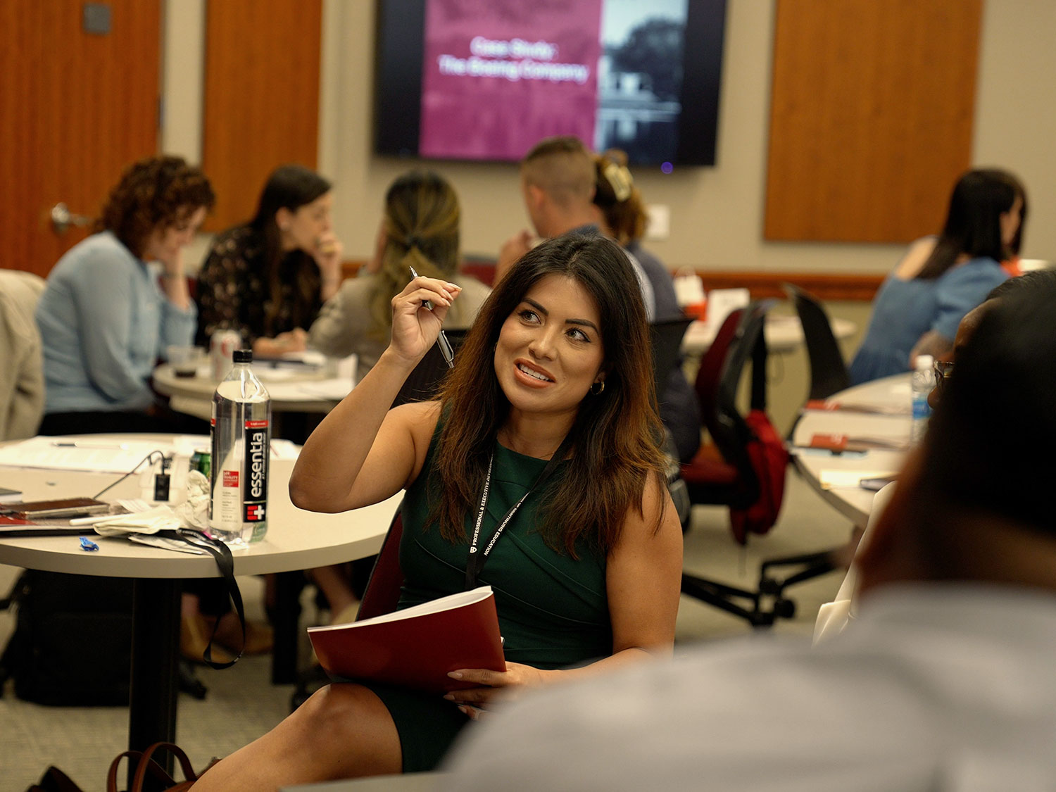 A woman sits in a chair, holding her hand in the air to emphasis her point.