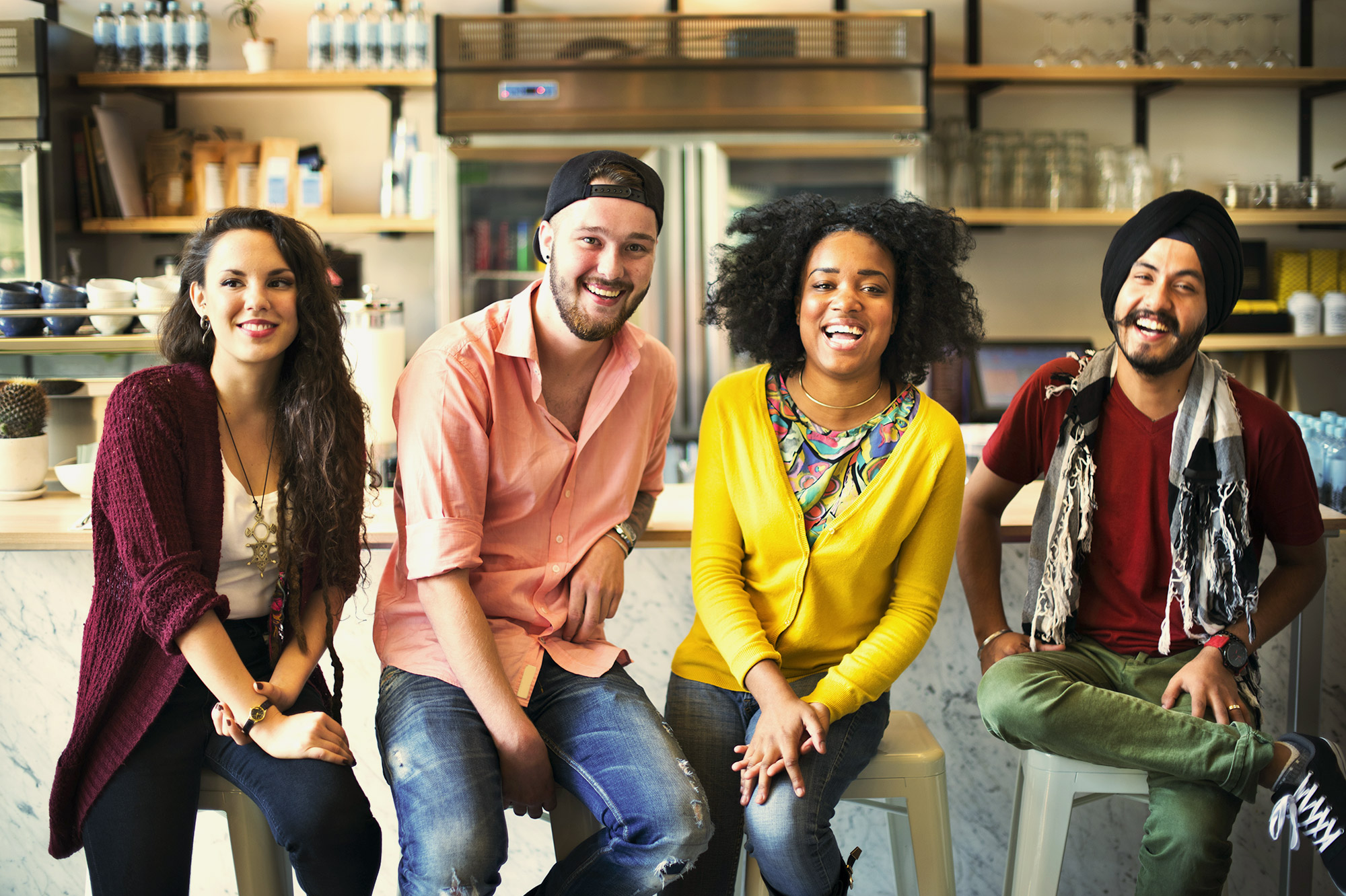 group of 4 culturally diverse people sitting on stools
