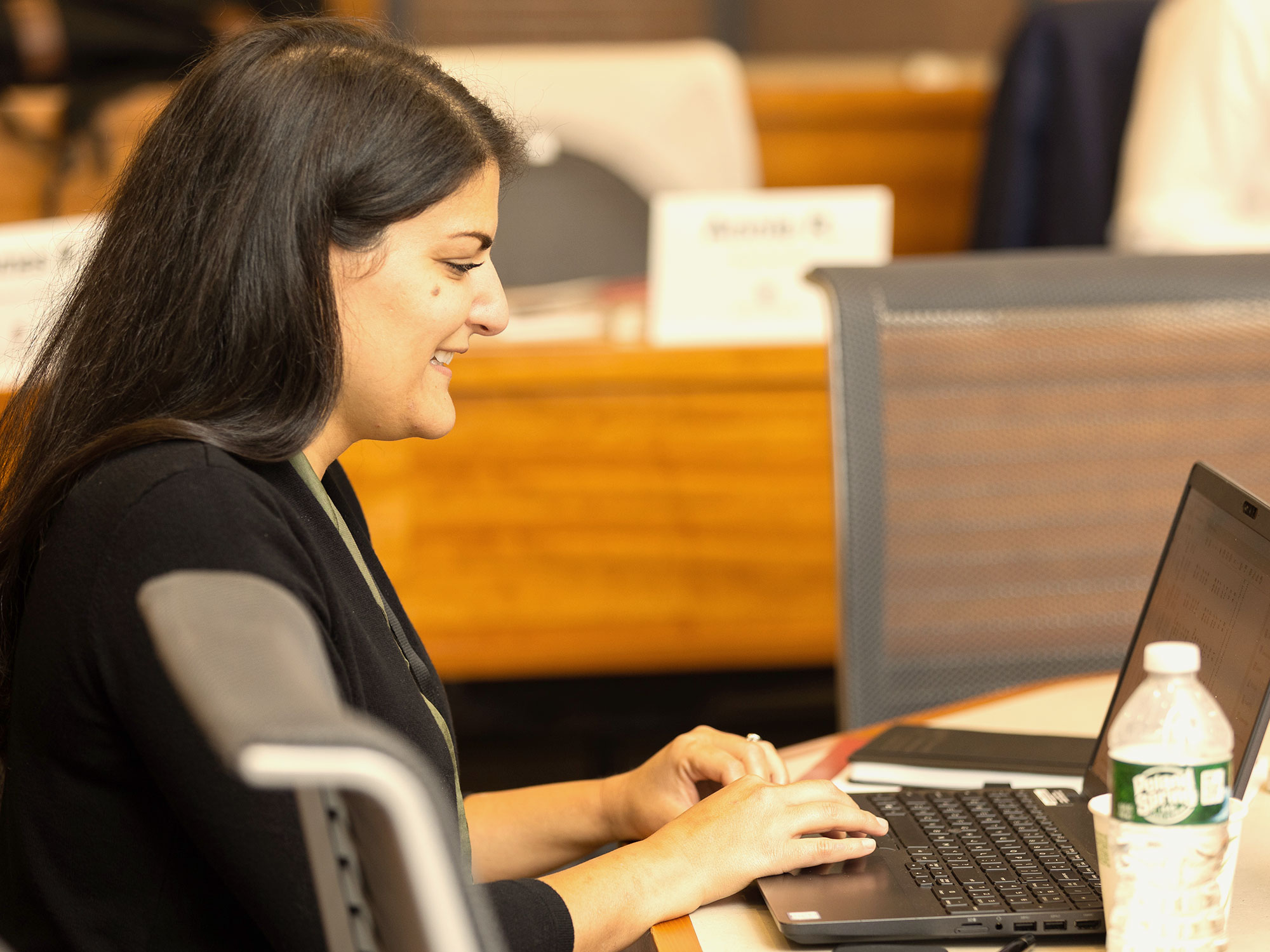 Woman smiling as she types on a laptop during a training session.