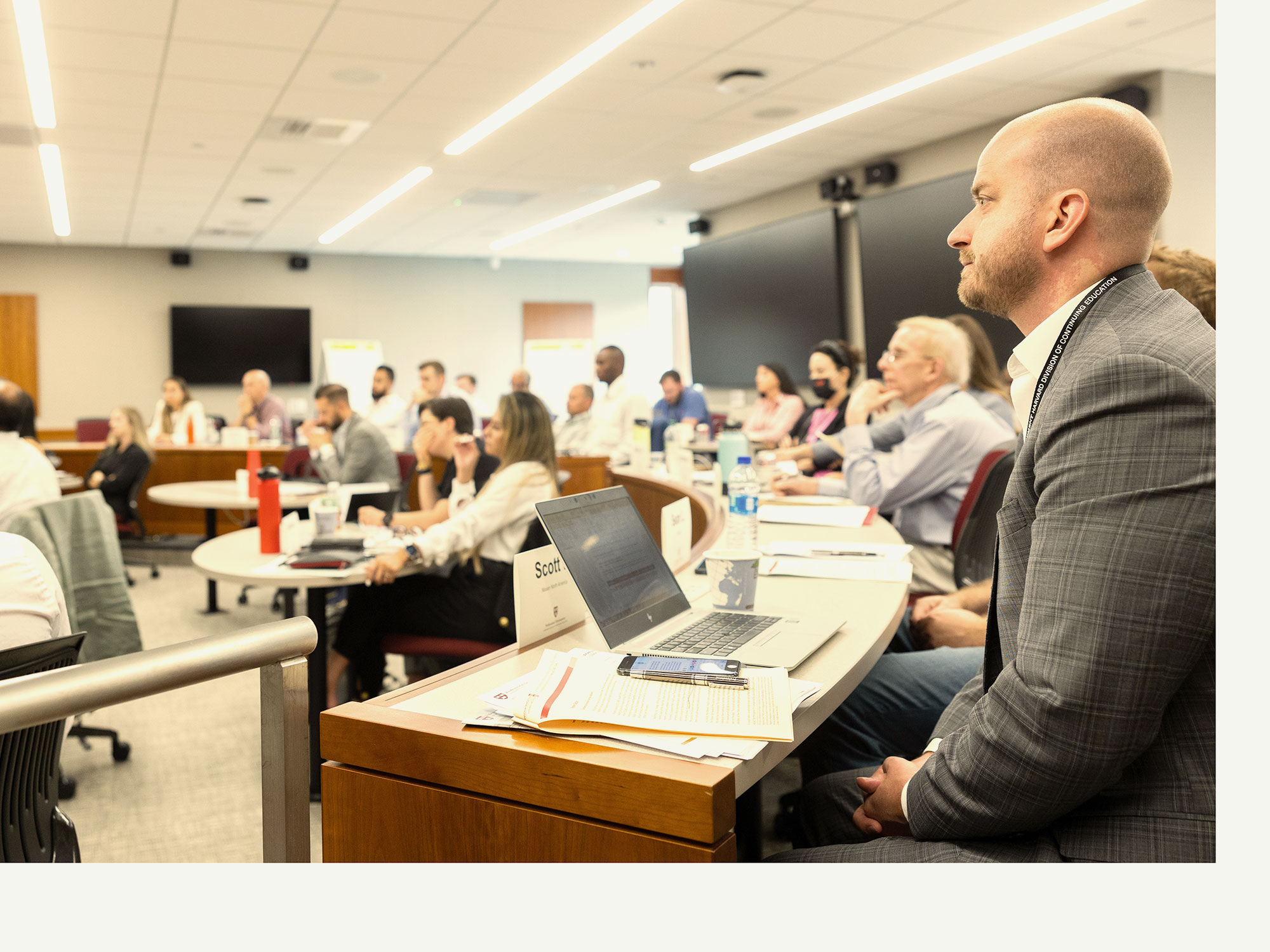 Business professionals attentively listening in a lecture-style classroom.