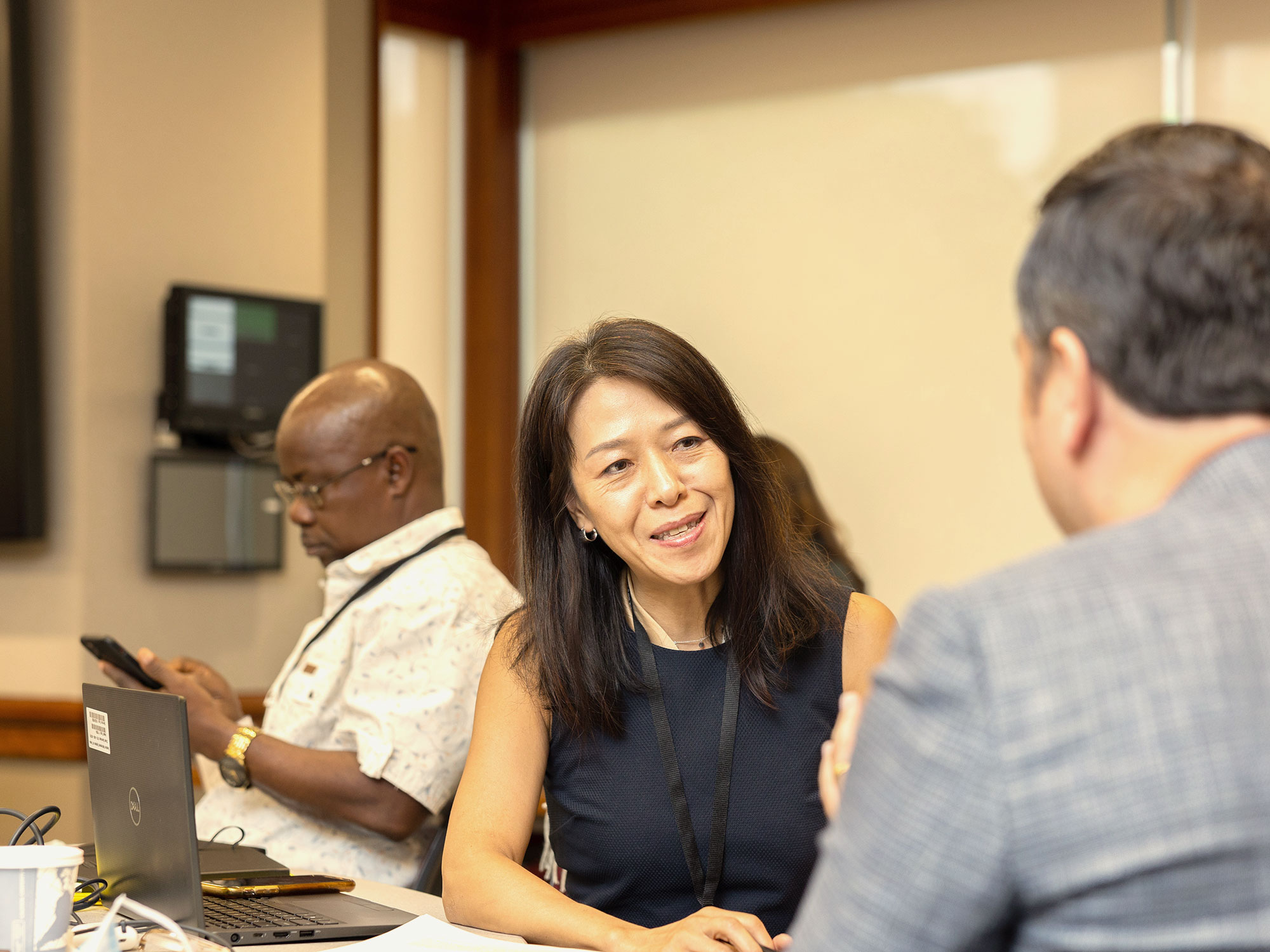 Woman smiling while engaging in a conversation with a man at a workshop table.
