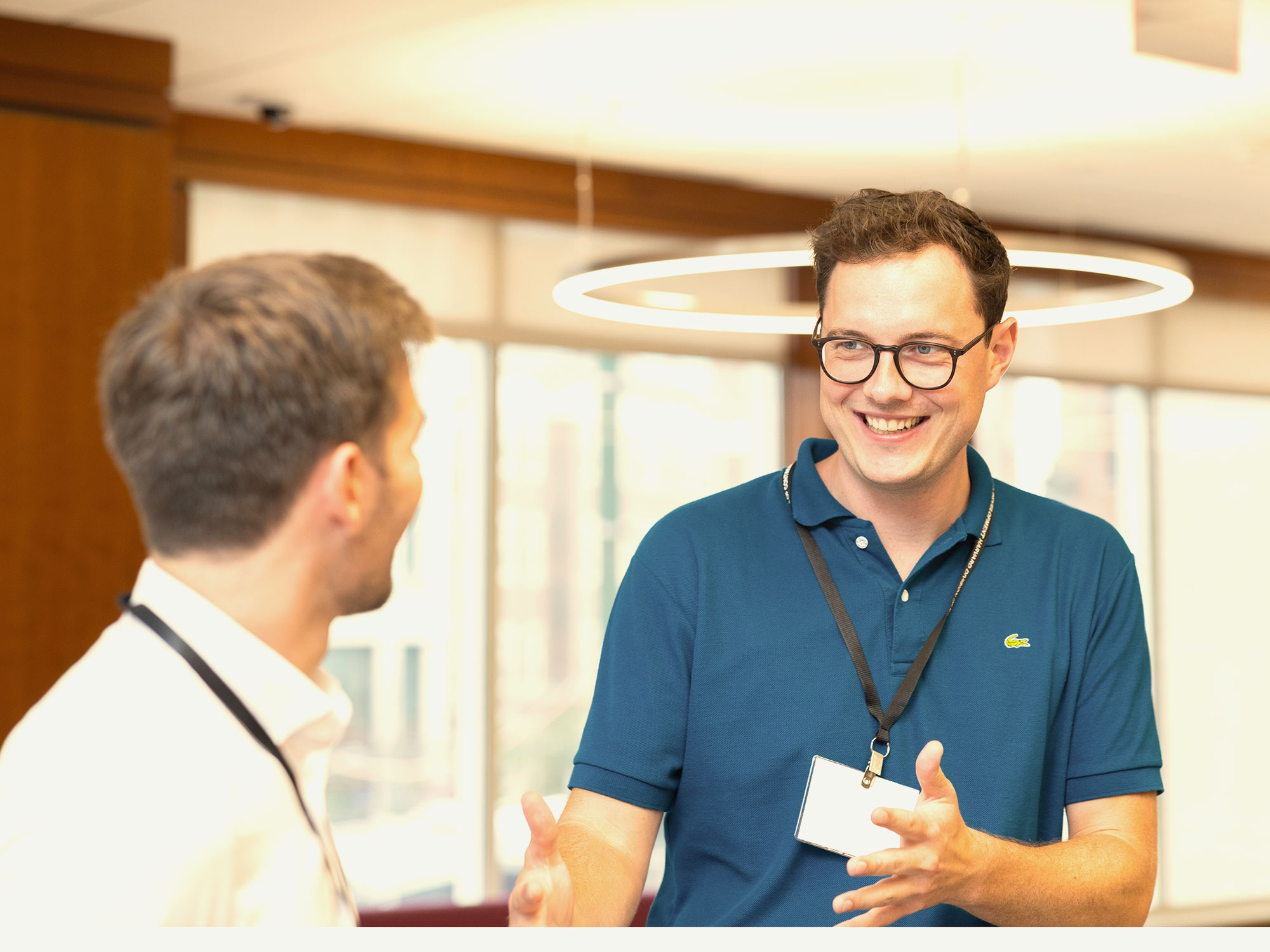 Man in blue shirt speaking animatedly to a classmate.